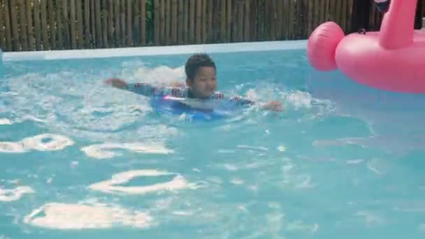 快乐的孩子在游泳池里玩耍 快乐的男孩在充气环上卷曲的头发在水里玩乐 在游泳池里享受暑假 暑假和假期 健康的户外运动 — 图库视频影像