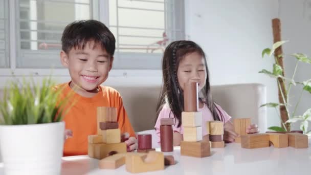 子供の男の子と女の子はコンストラクター木製のブロックの建物で遊んで 幸せな小さな子供たちは家で木のブロック積みボードゲームをプレイし アクティビティは創造的な学習 就学前と幼稚園のためのおもちゃ — ストック動画