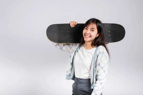 笑顔幸せな女性は肩の上にスケートボードを保持します 幸せなアジアの美しい若い女性励起ホールド手ロングボード スタジオショットコピースペースと白の背景に隔離されました スポーツ極端な — ストック写真