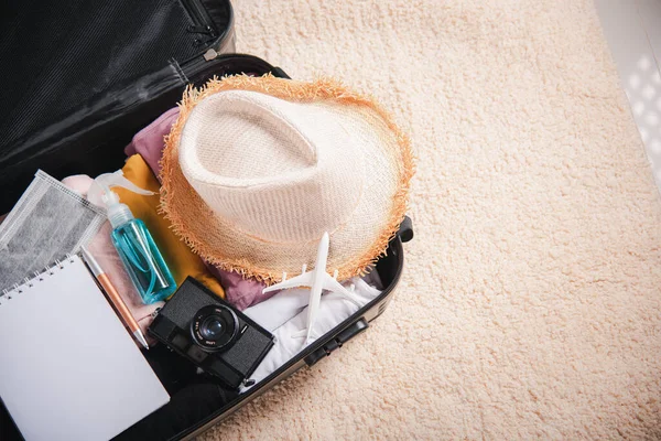 Open suitcase with traveler belongings clothes and accessories of things ready packing to be taken on summer holiday, Travel vacation luggage preparations concept, top view