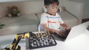 Satranç oynamak için dizüstü bilgisayardaki robot makine koluna Asya 'lı küçük çocuk programlama kodu, BTMM eğitimi E-öğrenme, Ders kontrolü robot kolu edinen komik çocuklar, Teknoloji Bilimi eğitimi alan çocuklar.