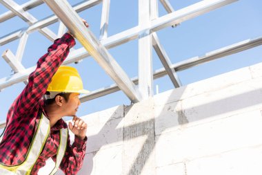 İnşaat işçisi ya da müteahhit ev iskeletini kontrol ediyor, inşaat alanında çelik çatı inşaatçısı çalışıyor.