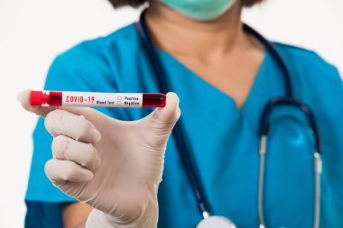 Mavi üniformalı hemşire laboratuarda beyaz arka planda izole edilmiş Coronavirus test kanını, COVID-19 ilaç salgın konseptini incelemek için bir maske takıyor.