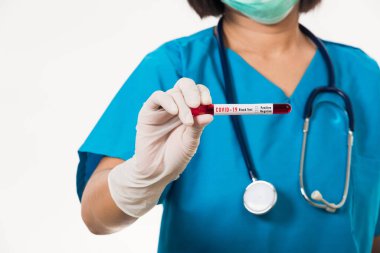 Mavi üniformalı hemşire laboratuarda beyaz arka planda izole edilmiş Coronavirus test kanını, COVID-19 ilaç salgın konseptini incelemek için bir maske takıyor.