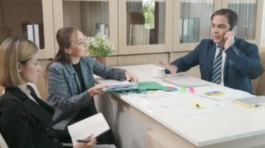 Patron cep telefonuyla konuşuyor ve sekreterinin evrak işlerini reddediyor. Ofiste beklemekle meşgul, yoğun bir iş günü.