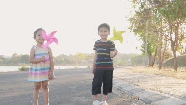 Tvillingsøstre Asiatisk Gutt Jente Som Løper Leker Med Vindmøllehjul Lykksalig – stockvideo