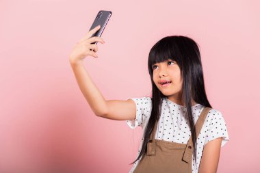 Asyalı çocuk 10 yıl boyunca cep telefonu kullanmaktan zevk aldı. Stüdyoda selfie çekti. Pembe arka planda izole edilmiş mutlu bir çocuk hayatı sürdü.