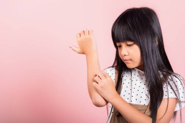 Asyalı küçük bir çocuk. Stüdyo çekiminde sivrisinek ısırığından dolayı kaşınan 10 yaşında. Pembe arka planda izole edilmiş.