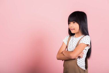 Stüdyoda kollarını kavuşturup gülümseyen 10 yaşındaki küçük Asyalı çocuk pembe arka planda izole edilmiş, kendine güvenen çocuk portresi, pozitif insan.