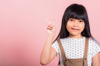 Asyalı küçük bir çocuk. 10 yaşında. Stüdyoda parmak hareketi yapıyor. Pembe arka planda izole edilmiş bir şekilde çekiliyor.