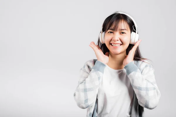 女人兴奋地微笑着 一边用蓝牙耳机听着音乐收音机 一边拿着电话录音 拍摄着孤独的白色背景 快乐的亚洲年轻女性一边听着现代科技手机 — 图库照片