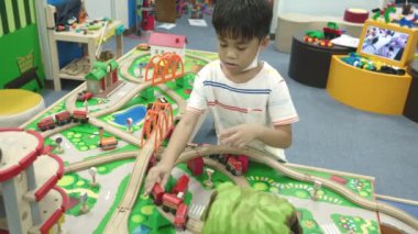 Mutlu Asyalı çocuklar eğlence merkezinde eğleniyorlar şişme şatoda oyuncak oynuyorlar, heyecanlı çocuk zıplama evlerinde oyuncak demiryolu oynuyor eğlence parkında oyun zamanı