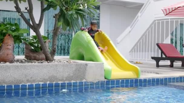 アジアの子供の男の子はウォータースライダーバーのおもちゃで屋外スイミングプールをプレイし 幸せな子供は家族の夏休み中にプール熱帯リゾートで遊んで 子供のためのスポーツ活動を泳ぐことを学ぶ — ストック動画
