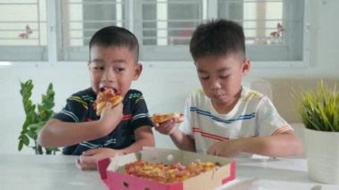 Mutlu Asyalı iki küçük çocuk 5 yıl boyunca evde birlikte büyük pizzalar yediler, çocuklar sağlıksız yemekler yediler, eğlenceli çocuklar pizza yediler, arkadaşlarıyla okul öncesi yemek yediler.