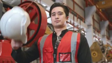 Güvenlik üniforması içinde genç bir adamın portresi göğsünde çapraz silah taşıyan, endüstriyel üretim fabrikasında çalışırken gülümseyen ve mutlu bir çalışan.