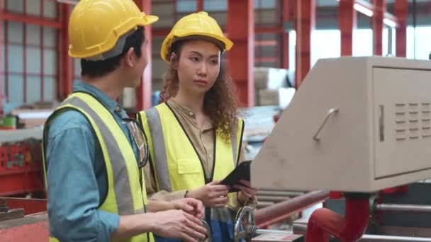 工業技術者の男性と労働者の操作女性の訓練は 彼らが工場の製造に機械について話している金属板アイロン機 2つのエンジニアリングは 安全ヘルメットを着用します — ストック動画
