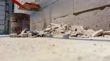 Eski beton ve tuğlaların yıkımından sonra çelik su tankında toplanan bir elektrikçi, kablo kanallarını döşemek için alçı duvarı kestikten sonra temizlik yapıyor.
