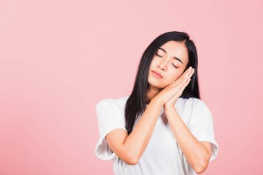 Asyalı güzel bir genç kadın, duyguları varmış gibi yaptı uyuyormuş gibi yaptı. Yorgun gözler kapalı. Yüze yakın eller hayal etti, pembe arka planda stüdyo çekimi yaptı.