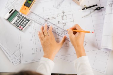 Mimari proje işyeri. Mimarlık bürosundaki masa başı tamir aletleri için ev planı taslağı üzerinde cetvel olan mimar çizimi, mimarlık taslak çizimi, mühendislik araçları