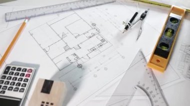 Mimari proje işyeri. Mimarlık bürosundaki masa başında tamir aletleri olan ev planı tasarım kağıtlarının üst görünümü, Mühendislik mimari tasarım araçları konsepti