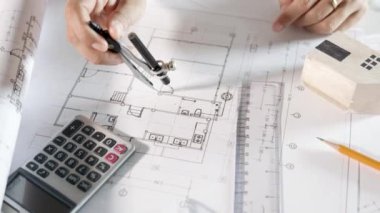 Mimari proje işyeri. İnşaat projesini çizen mühendis, mimarlık bürosundaki masa masasındaki tamir araçları için ev planı taslak kağıdına bölücü pusula çizen mimar.