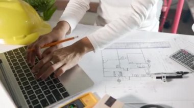 Mimari proje işyeri. Mimarlık bürosundaki masa başı masa üzerinde cetvel üzerinde cetvel çizmeden ya da taslak çizmeden önce evin tasarımını gözden geçirmek için dizüstü bilgisayar klavyesi yazmayı seçin