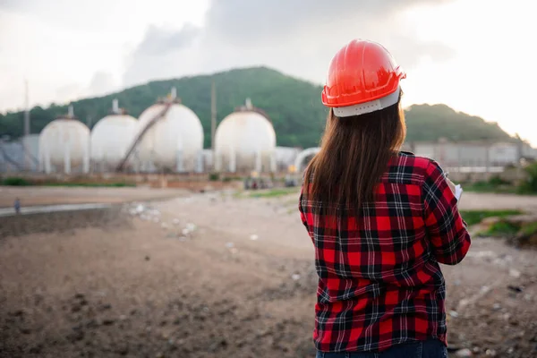 Petroleum Engineers. Happy Asian worker woman in oil chemical industry worker working visual inspection list on clipboard in plant, do Action of worker do safety checklist which is clipped