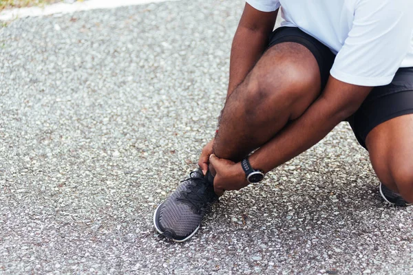 Kapatın Asyalı genç spor koşucusu. Siyah adam kol eklemli el takıyor. Ayak bileği burkulduğu için bacak ağrısı çekiyor.