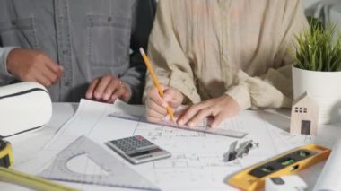 Mimari ekip toplantısı ortaklık ve mühendislik ile birlikte çalışarak mimari inşaat projesinde danışmanlık ve çalışma. Taslak kağıt planları üzerinde düzenleme ve çizim yapıyorlar.