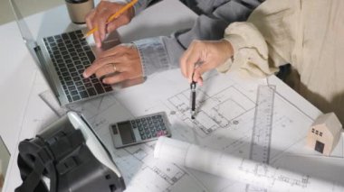 Mimari takım toplantısı, dizüstü bilgisayarla mimari inşaat projesi için danışmanlık ve çalışma. Tasarım planları, mimarlık ve mühendislik planları üzerinde düzenleme yapıyorlar. Birbirlerine yardım ediyorlar.