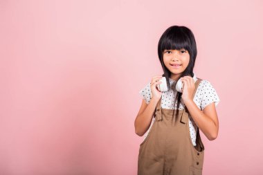 Asyalı küçük bir çocuk. 10 yaşında, gülümseyen bir çocuk. Stüdyoda kablosuz kulaklık takıyor.