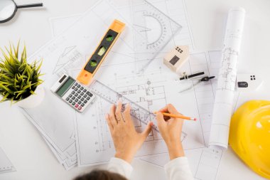 Mimari proje işyeri. Mimarlık bürosundaki masa başı tamir aletleri için ev planı taslağı üzerinde cetvel olan mimar çizimi, mimarlık taslak çizimi, mühendislik araçları