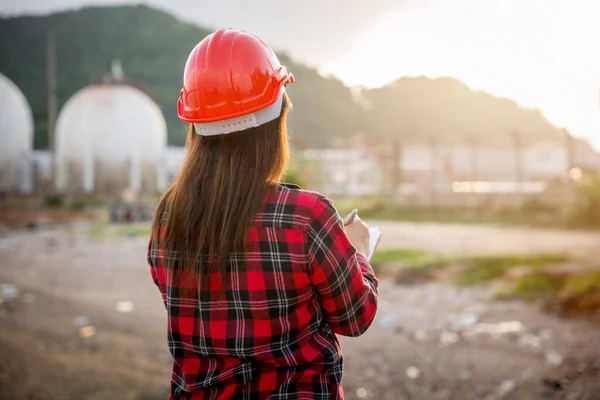 Petroleum Engineers. Happy Asian worker woman in oil chemical industry worker working visual inspection list on clipboard in plant, do Action of worker do safety checklist which is clipped