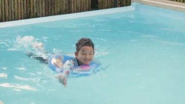 Mutlu genç, kıvırcık saçlı, şişme yüzüklü, suda eğlenen ve yaz tatilinde havuzda eğlenen mutlu çocuk, havuzda oynayan çocuk, yaz tatilleri ve tatil konsepti.