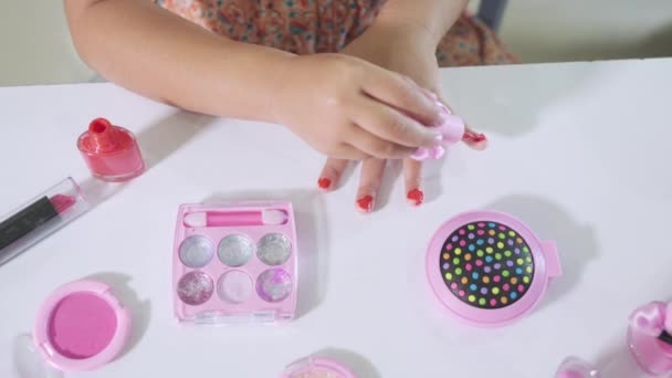 アジアの愛らしい面白い女の子作るメイクディップ筆にボトルにペイント爪ポリッシュ赤爪ニス自分自身 女性であることを学ぶ活動 幸せな子供は化粧品おもちゃで美しい構成されています — ストック動画
