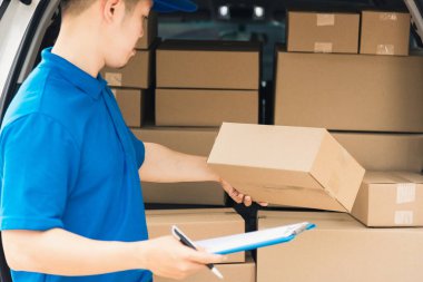 Üniformalı Asyalı genç kurye evrakları pano kontrol listesi posta kutularını müşteriye servis sevkiyatı için bir arabanın yanında tutuyor, çevrimiçi alışveriş hizmeti kavramları