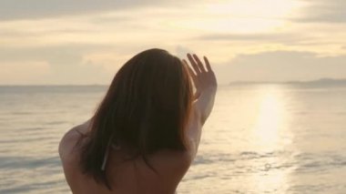 Geriye bakış, güzel kadın bikini mayo giyiyor tropik plajda elleri ile kalp işareti yapıyor mutlu Asyalı seksi kadın parmaklarıyla şekil veriyor gün batımının dışında tatilde, yaz tatili