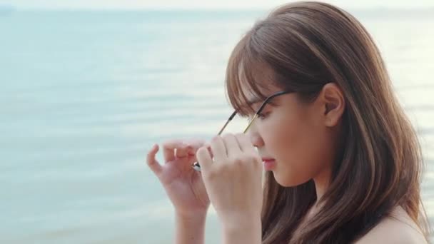 美丽的亚洲女人 戴着太阳镜在热带天堂的海滩上微笑着 快乐的女人穿着比基尼泳衣在暑假旅行时戴着有趣的眼镜 — 图库视频影像