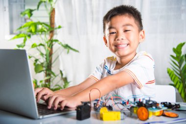 Asyalı çocuk, Arduino robot arabası için dizüstü bilgisayarla kodlama ve programlama öğreniyor, küçük çocuk öğrenciler, araba oyuncağıyla bilgisayar kodları yazıyorlar, STEAM eğitim teknolojisi kursu öğreniyor.