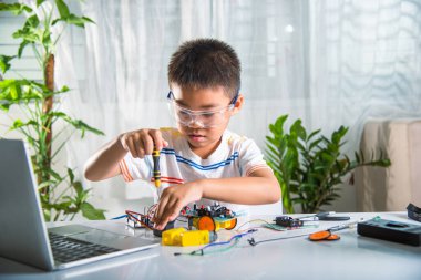 Küçük çocuk oyuncağı monte etmek için tornavidayla cevizi sıkıyor, Asyalı çocuk evde Arduino robot araba ev ödevi yapıyor, eğitim yapay zeka atölyesi dersi öğreniyor.