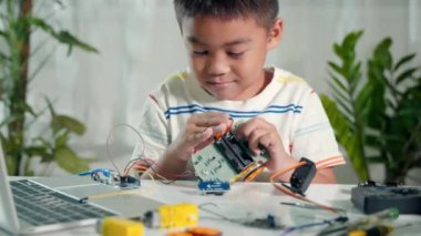 Küçük çocuk oyuncakları birleştirmeye çalışıyor, Asyalı çocuk Arduino robot araba ödevinde tekerlek birleştiriyor, elektronik yapay zeka atölyesi çevrimiçi okul dersi yaratıyor.