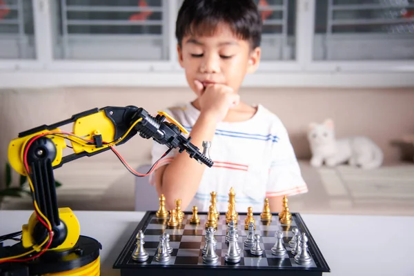 Asian little boy thinking and wait robot arm playing chess, STEM education E-learning, Funny children learning successful getting a lesson control robot arm game, Technology science education concept