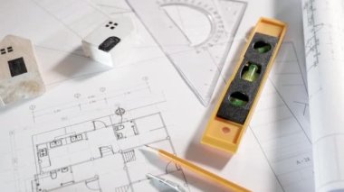 Mimari proje işyeri. Mimarlık bürosundaki masa başında tamir aletleri olan ev planı tasarım kağıtlarının üst görünümü, Mühendislik mimari tasarım araçları konsepti
