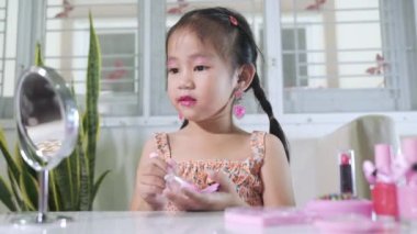 Asyalı sevimli küçük kız makyaj yapıyor aynaya ve yanağa bakıyor pudra için pofuduk fırça, kadın olmak için etkinlik öğreniyor, mutlu çocuk güzel makyaj yapıyor kozmetik oyuncağıyla.
