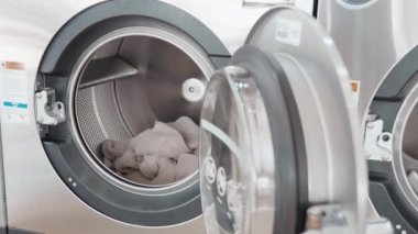 Kadın elleri kirli çamaşırları ve havluları ön yükleme makinesine koyuyor, ev hanımı çamaşırları yüklüyor, yeni teknoloji elektronik cihazlar farklı programlar.