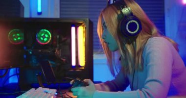 Oyun bitti, kaybettin. Kızgın Asyalı oyuncu oyun kulaklığı takıyor bilgisayar ekranında oyun konsolu oyunu oynuyor PC neon lambası açık, oyunu kaybettiği için üzgün hissediyor, oyuncu mutsuz E-Sport