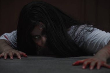 Kanlı dişi zombi. Kanlı Asyalı kadın hayalet. Karanlık evdeki korkunç korku tüyler ürpertici sürünme yavaş yavaş yayılıyor. Saç kaplaması kameraya bakıyor, Cadılar Bayramı festivali konsepti.