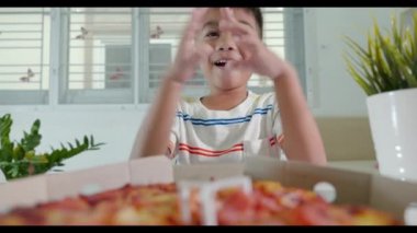 Mutlu Asyalı küçük çocuk 5 yıl açık pizza kartonu ve evde çok şaşırmış ve mutlu bir şekilde, çocuklar sağlıksız yiyecekler yiyor pizza yiyen heyecanlı komik çocuk, kutunun içinde