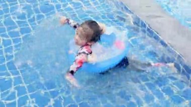 Asyalı çocuk küçük kızlar şişme oyuncak yüzüğünde açık havuzda yüzüyor mutlu çocuk yaz tatilinde tropikal havuzda oynuyor çocuklar için yüzme sporu öğreniyor.