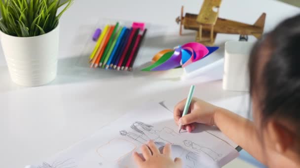 Asiatische süße Kind Vorschulkind sitzt auf dem Tisch lächelnd sie zeichnen und schreiben Bild mit Bleistift zu Hause zu lernen Kunst Hausaufgaben, Happy Child kleines Mädchen Zeichnung Cartoon auf Papier, bevor die Farbe malen